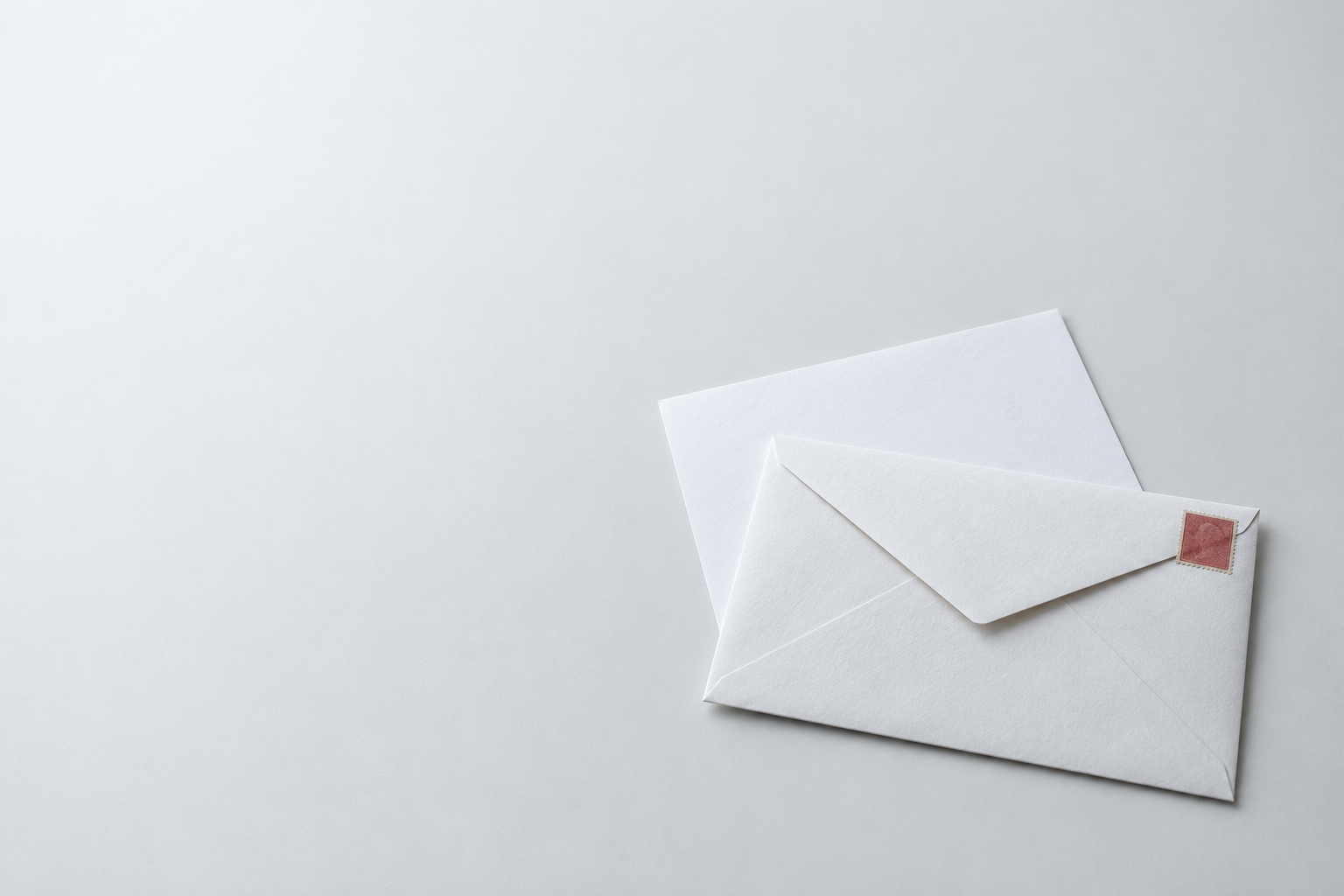 A white envelope and a blank letter on a light tabletop.